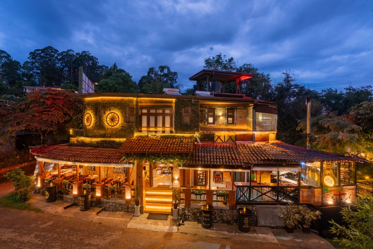 AK Ristoro on Passara Road, Ella, at blue hour: the timber restaurant lit amber under a deep blue sky, its wagon wheels and steps glowing